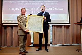 Tomasz Żuchowski gives Prof. Claude Van Rooten a replica of the historical map of Poland